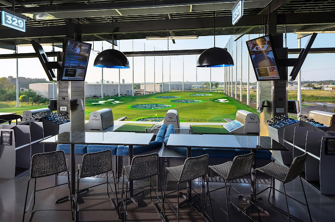 Golfers practicing swings at Nashville’s indoor driving range, nets catching high-flying balls