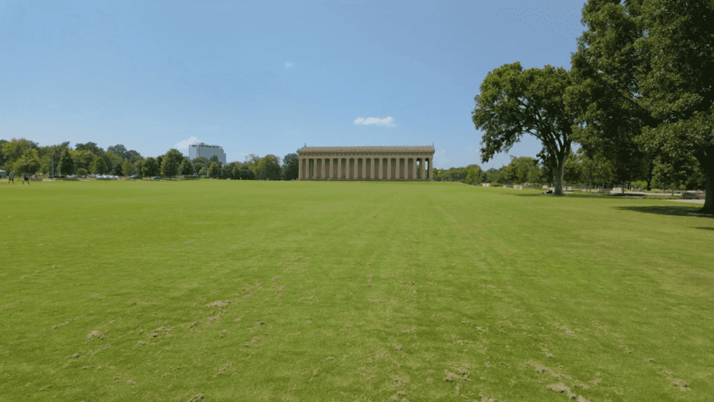 Full-side view of the Nashville Parthenon, a full-scale replica of the Athenian Parthenon, with 46 Doric columns and a grand pediment under a clear blue sky