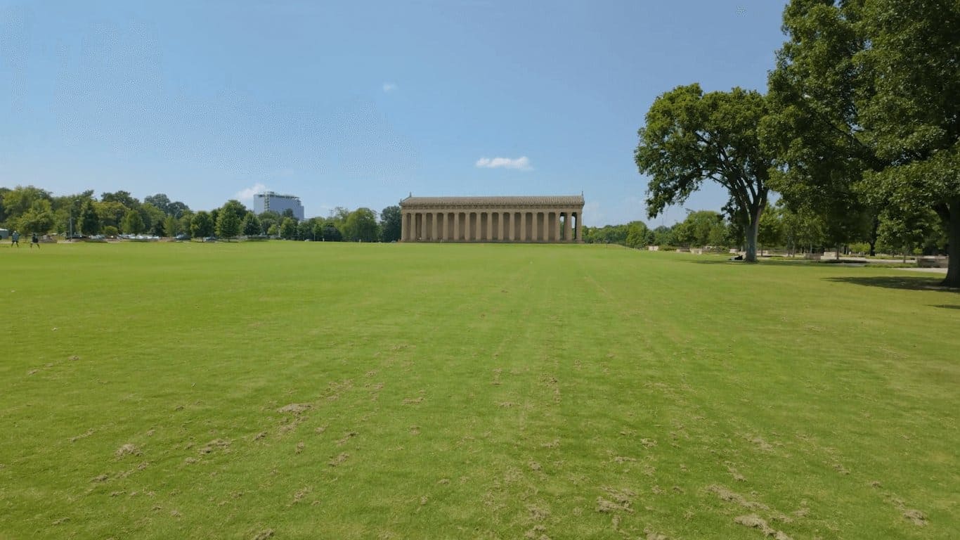 Wide view of the Nashville Parthenon replica visible across green lawns of Centennial Park on a sunny summer day Tennessee