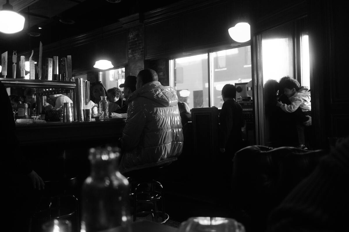 Locals savor Nashville's nightlife in a cozy black-and-white bar, glowing with warm light and lively chatter