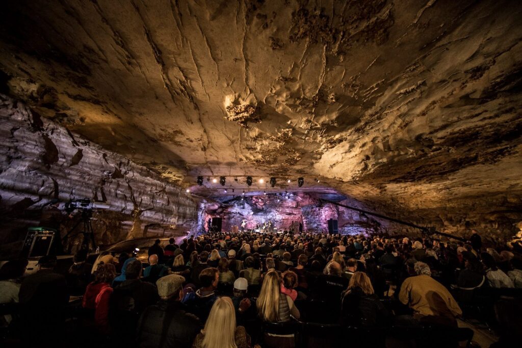 Underground cave concert venue with high rocky ceiling and crowd gathered below for performance in Nashville's music attraction