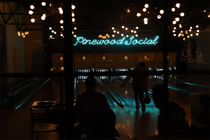 Glossy lanes at a Nashville bowling alley, neon lights glowing as a ball rolls toward the pins