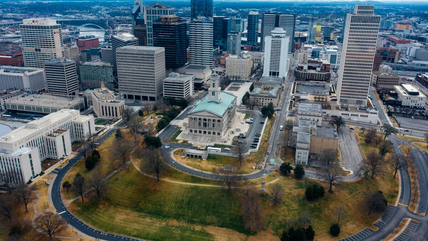Aerial view of city Tennessee capitol building surrounded by green space with downtown skyscrapers in background