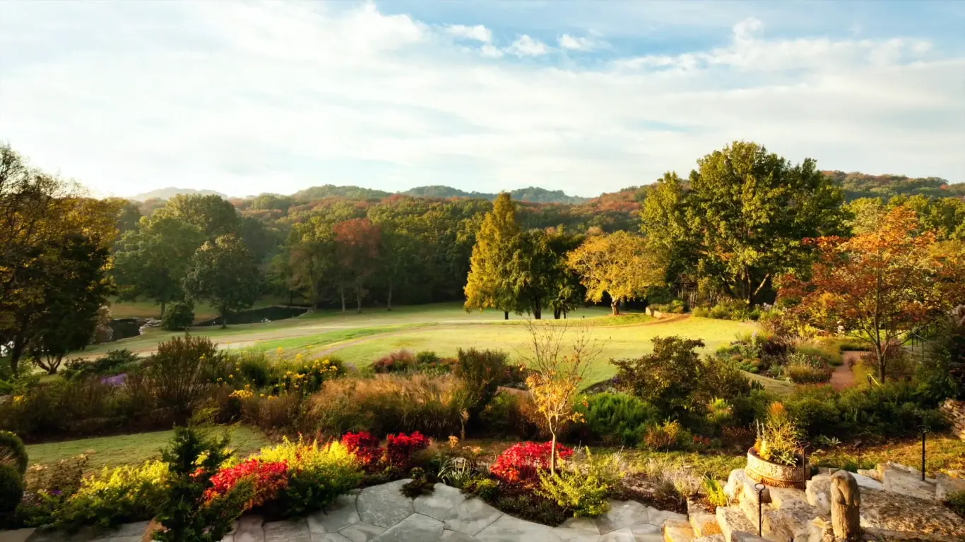 A scenic autumn landscape near Nashville features lush gardens and gently rolling hills under golden light