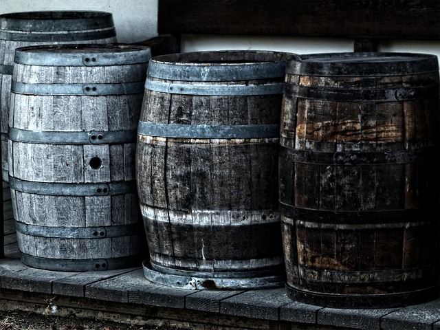 Three hidden weathered wooden barrels stacked side by side at a brewery in a ruined factory