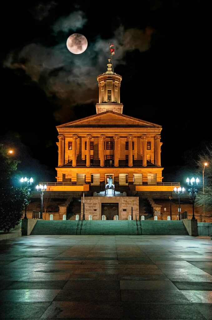 Tennessee State Capitol illuminated at night with full moon backdrop highlighting the Ionic temple design columns
