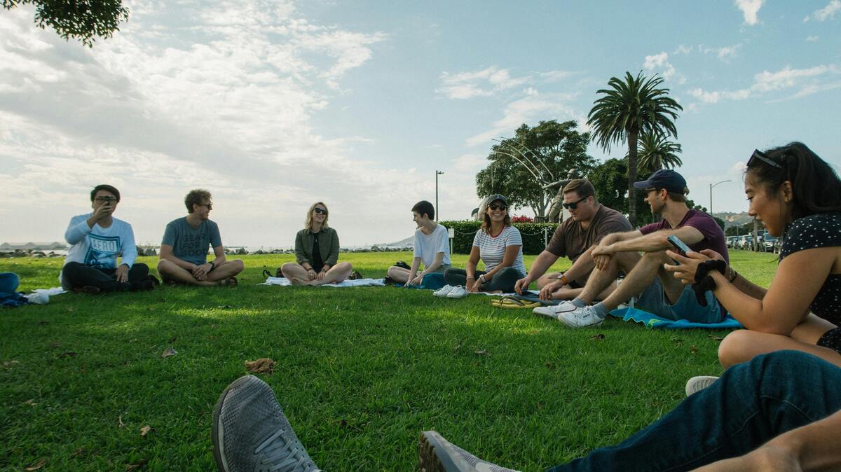 Friends gather on lush grass, enjoying Nashville's outdoor cultural vibe with palm trees and blue skies