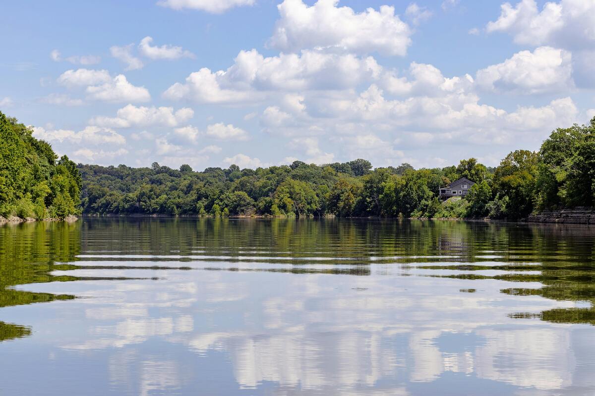 Outdoor Nashville fun lakeside scene with perfect cloud reflections in calm water surrounded by lush green forest trees
