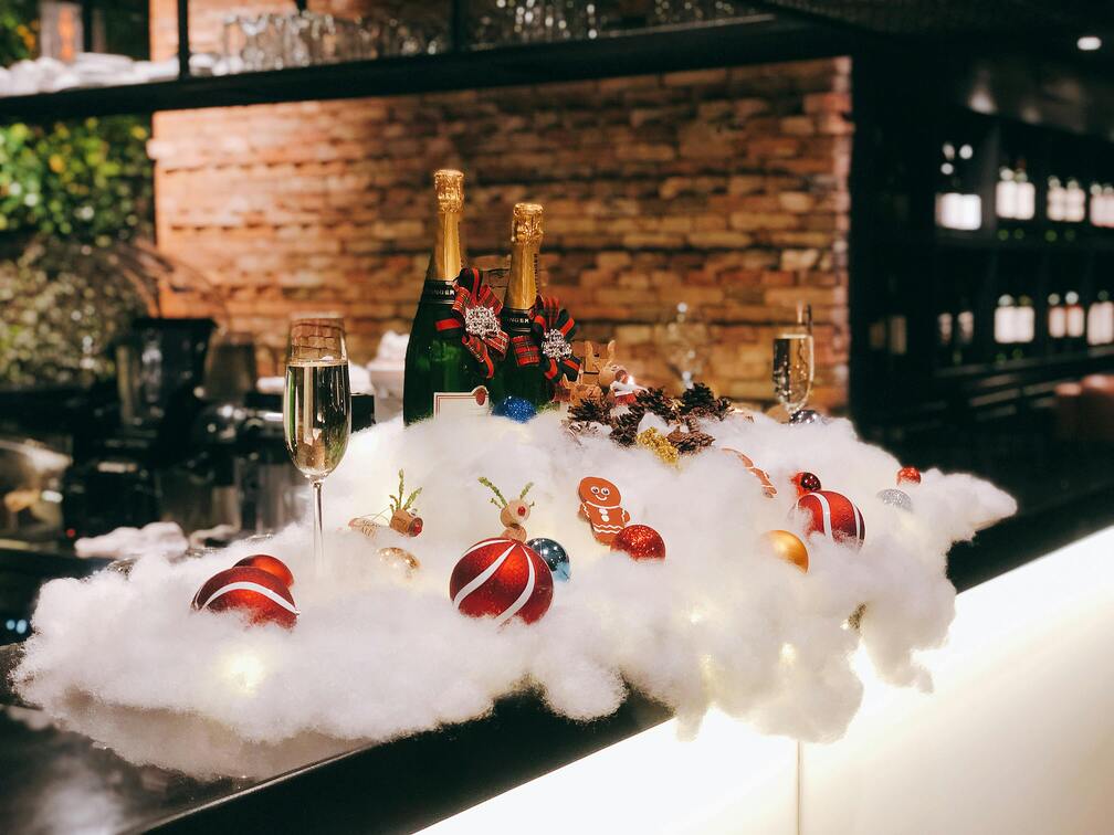 Champagne bottles and Christmas ornaments arranged on fluffy white cotton resembling snow at Nashville's Christmas bar