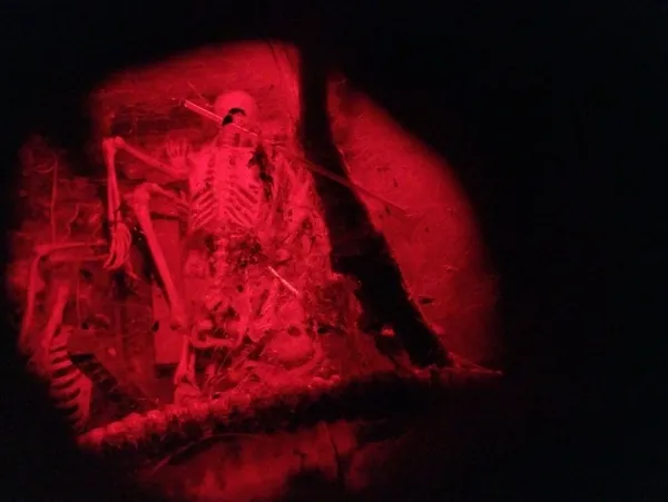 A skeleton illuminated by red lights and visible from hole in a dark bar setting at Red Door Saloon