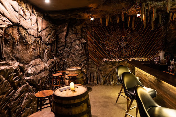 themed bar interior at Kung Fu Saloon with stone walls, skeleton decoration, barrel tables and bar seatin