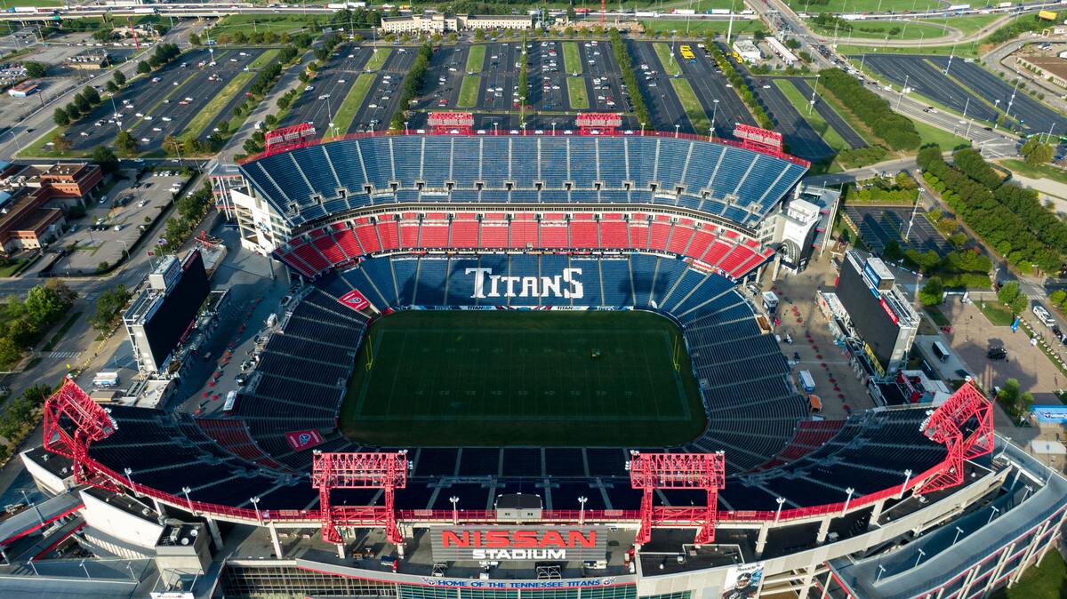 Outdoor Nashville fun sports venue aerial view of Titans stadium with red seats, green field, and surrounding parking lots
