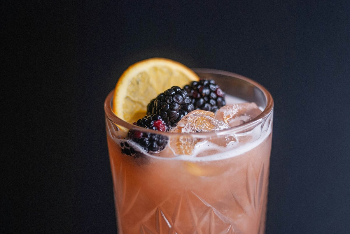 Craft cocktail with blackberries and orange garnish served at top-rated best East Nashville restaurants for upscale dining