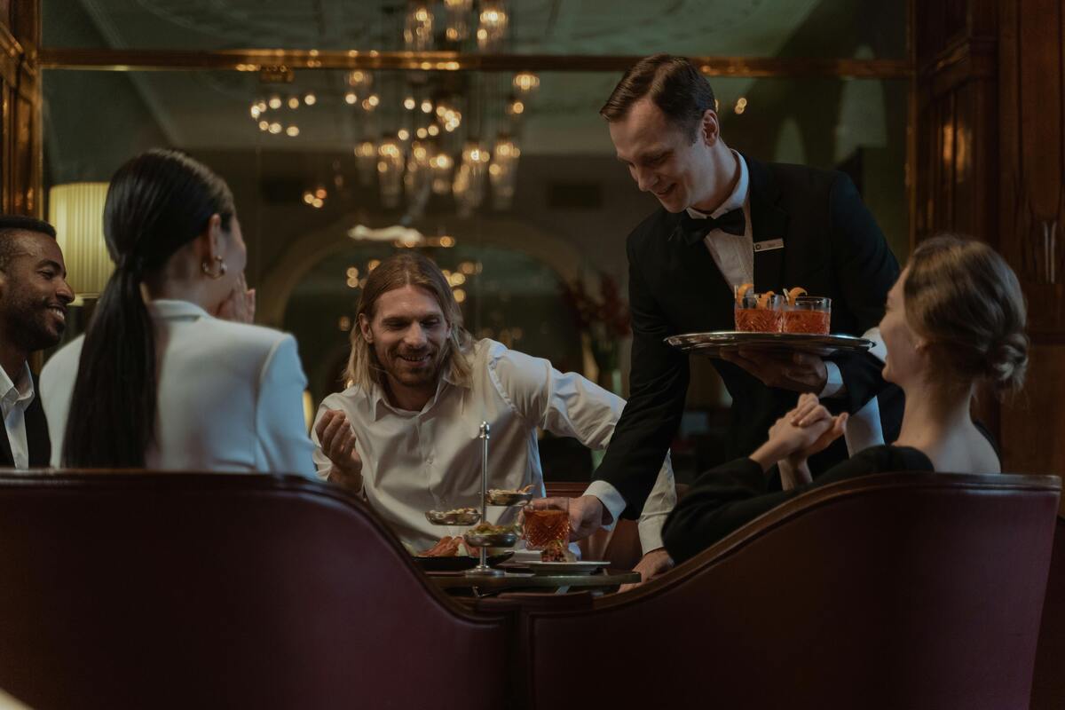 Elegant dining experience with an attentive server presenting craft cocktails, beautifully showcasing Nashville's sophisticated evening restaurant