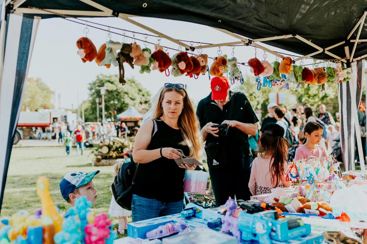 Family browses a colorful Nashville craft market admiring stuffed toys and handmade goods under festive tents