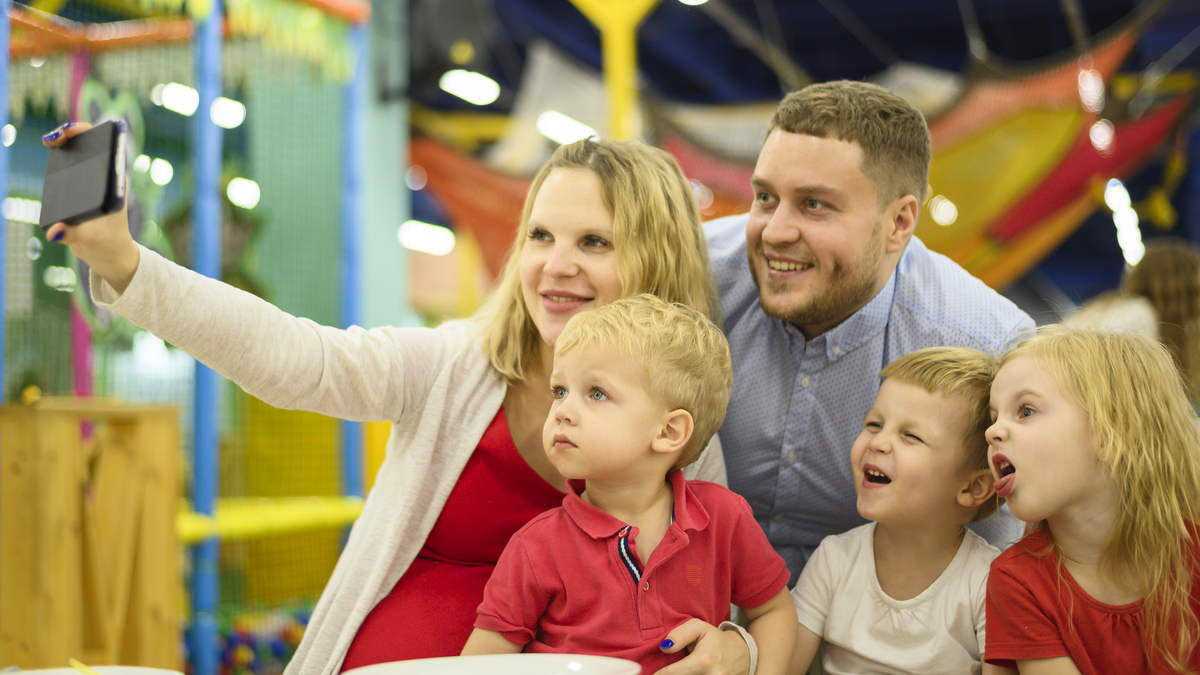 Family takes a selfie together at an indoor Nashville play center with bright colorful climbing structures 