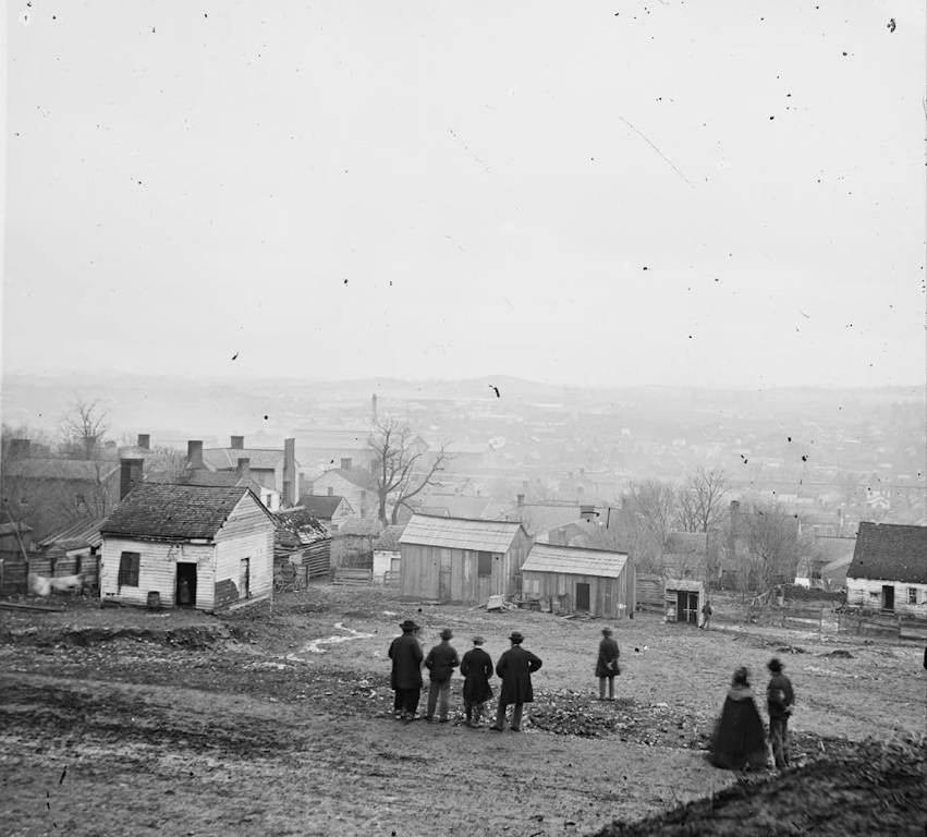 Rural outskirts of early Nashville with small wooden homes on hillside, people overlooking distant city below