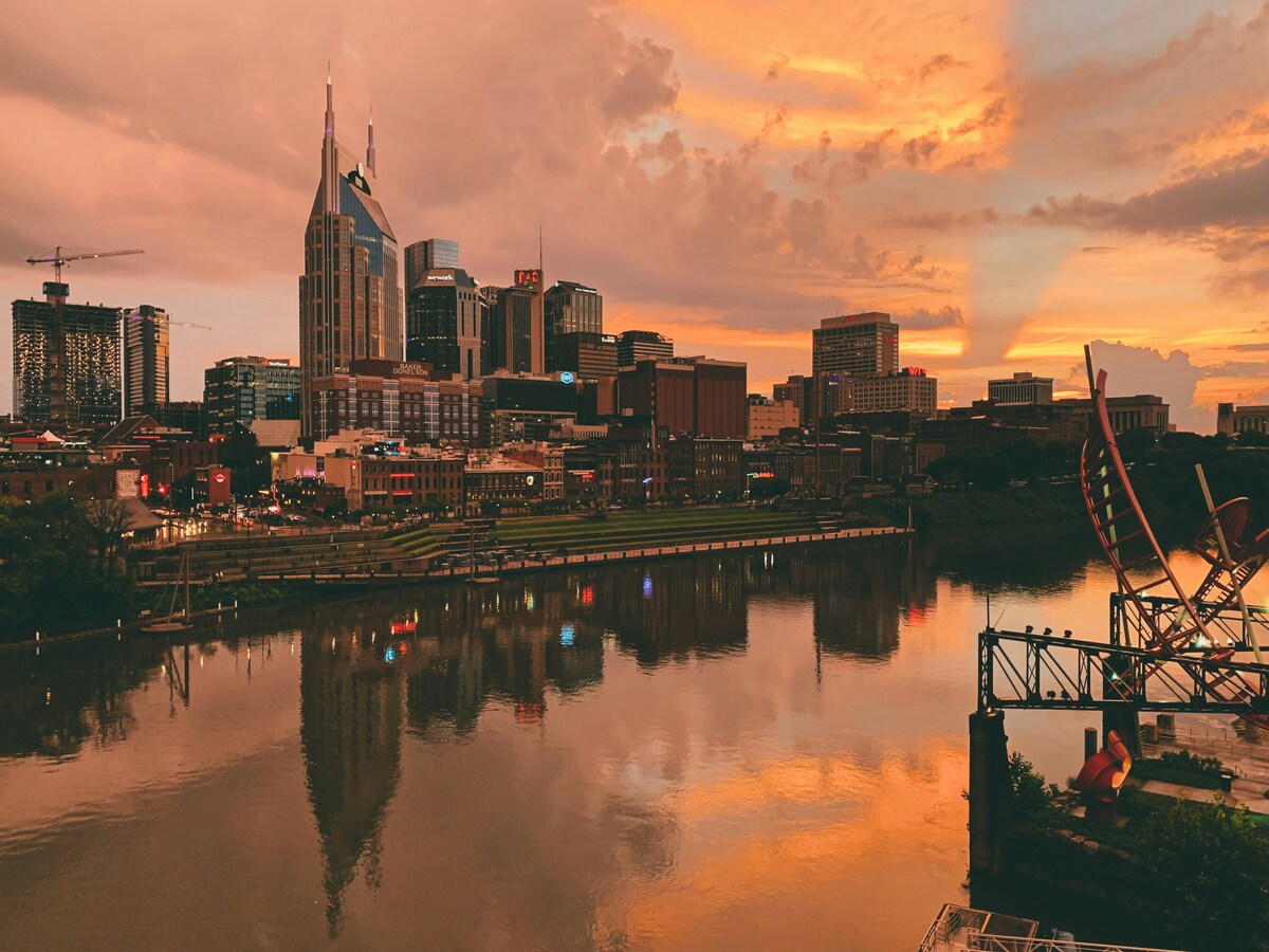 Outdoor Nashville sunset cityscape reflecting in Cumberland River with iconic AT&T Building and glowing sky colors