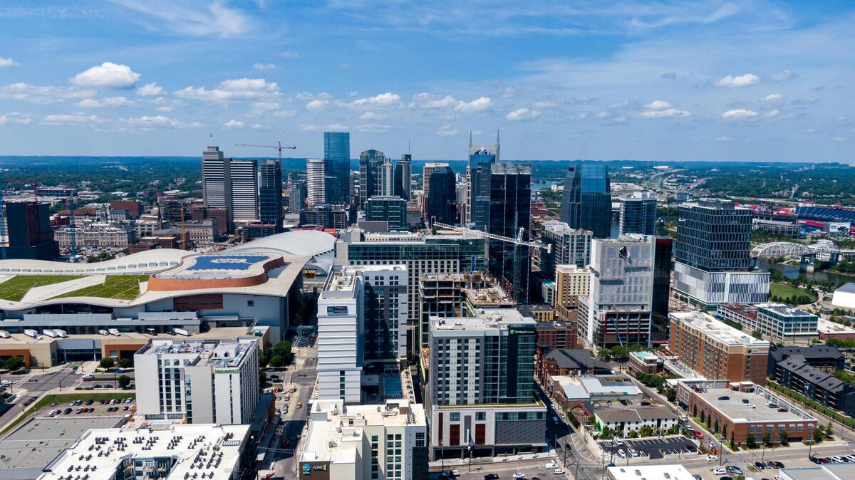 Aerial view of Nashville downtown with "Batman Building," convention center, expanding urban development against blue sky