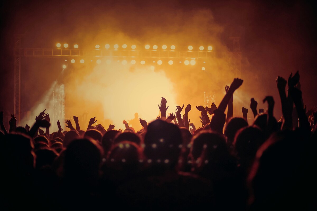 Outdoor Nashville fun concert with energetic crowd raising hands under dramatic stage lights and smoky atmosphere
