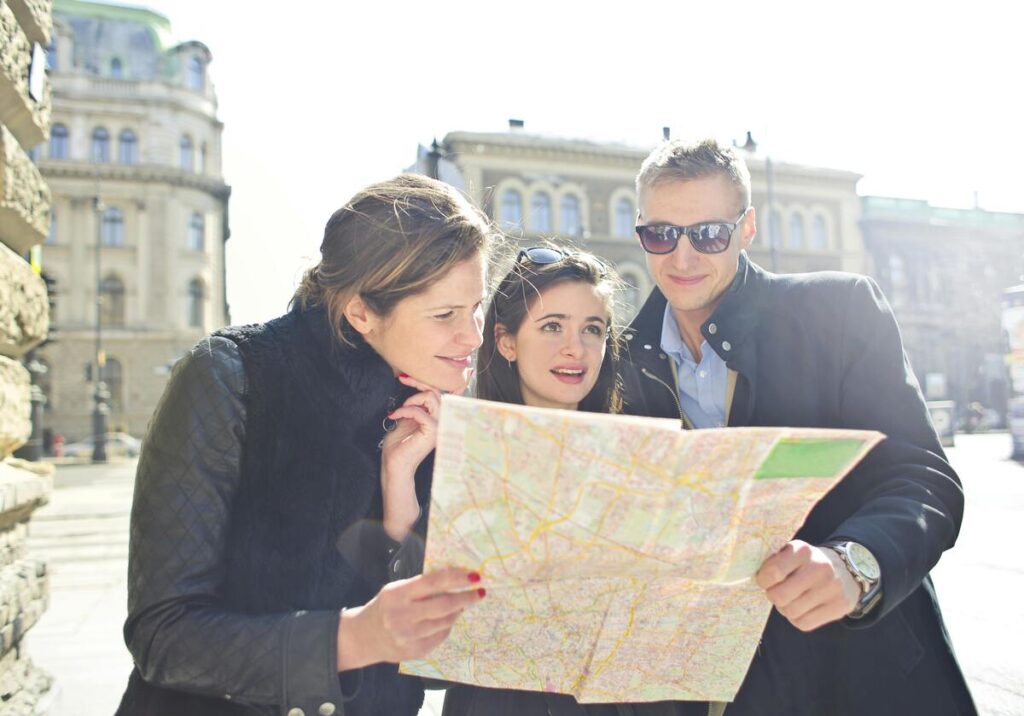 Three tourists intently consulting a city map together while exploring Nashville's historic downtown architecture and attractions