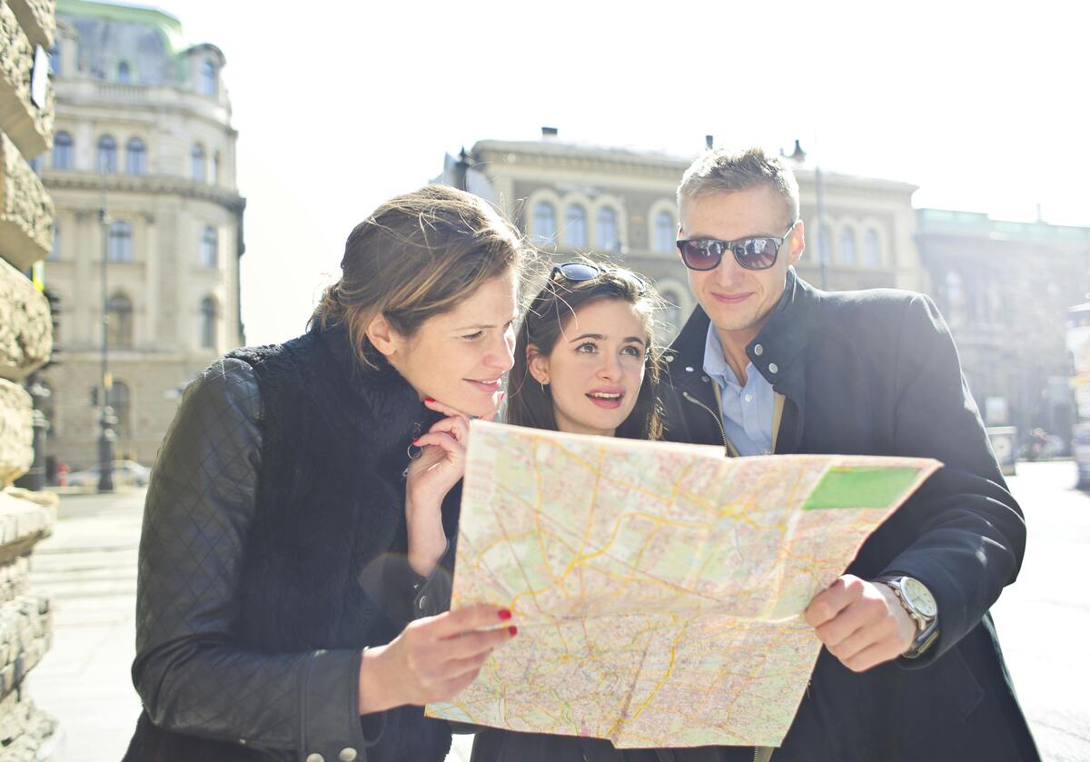 Three tourists intently consulting a city map together while exploring Nashville's historic downtown architecture and attractions