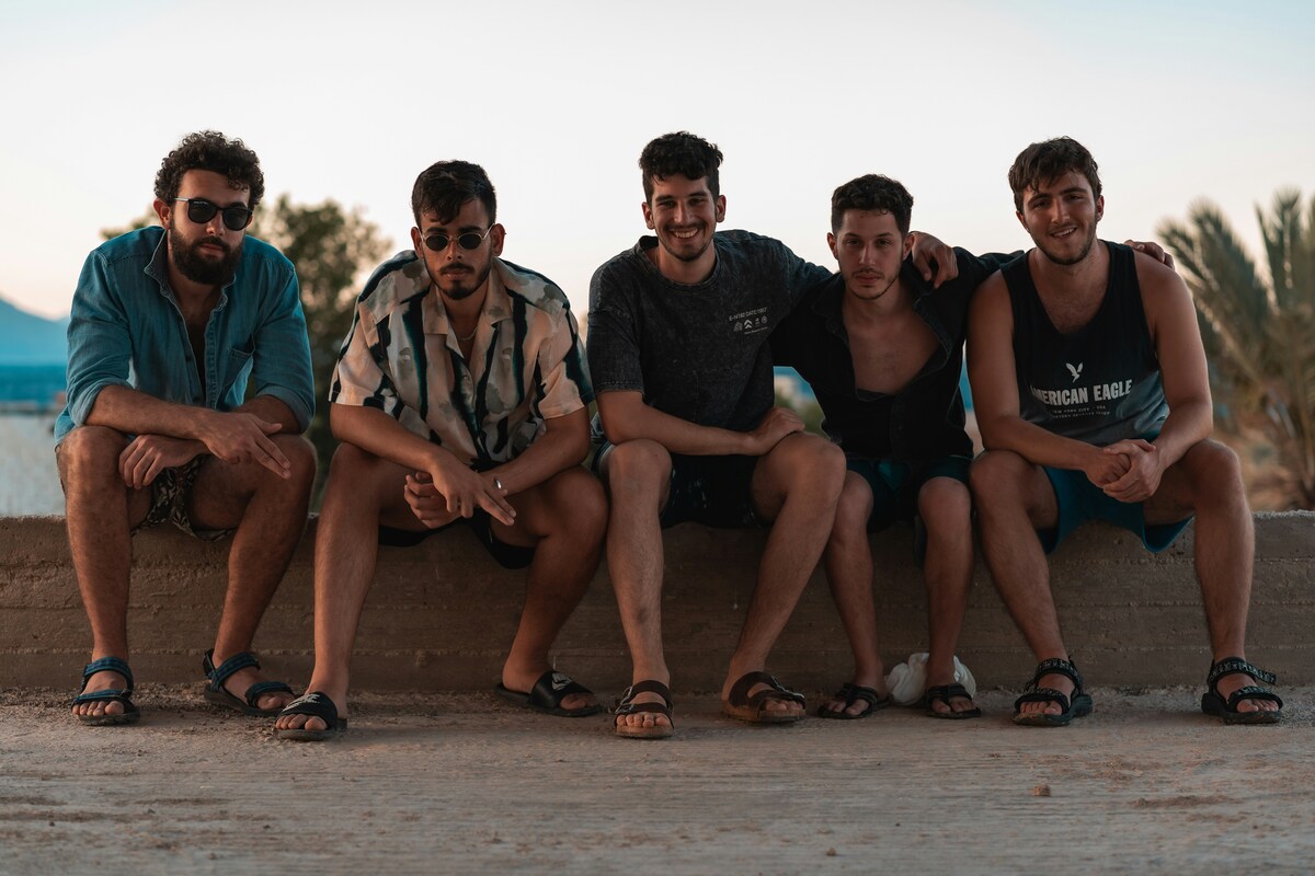 Friends laughing and relaxing under a vibrant sunset at a scenic riverbank during their Nashville trip