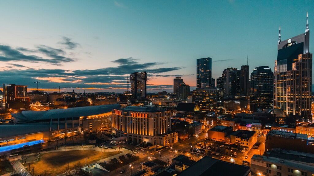 Nashville downtown skyline at dusk featuring Bridgestone Arena, AT&T Building, and illuminated skyscrapers under dramatic sunset sky.RetryClaude can make mistakes. Please double-check responses.