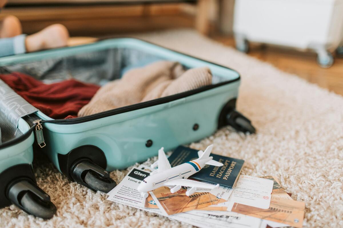 Open turquoise suitcase with clothes being packed alongside passport and travel documents for Nashville trip
