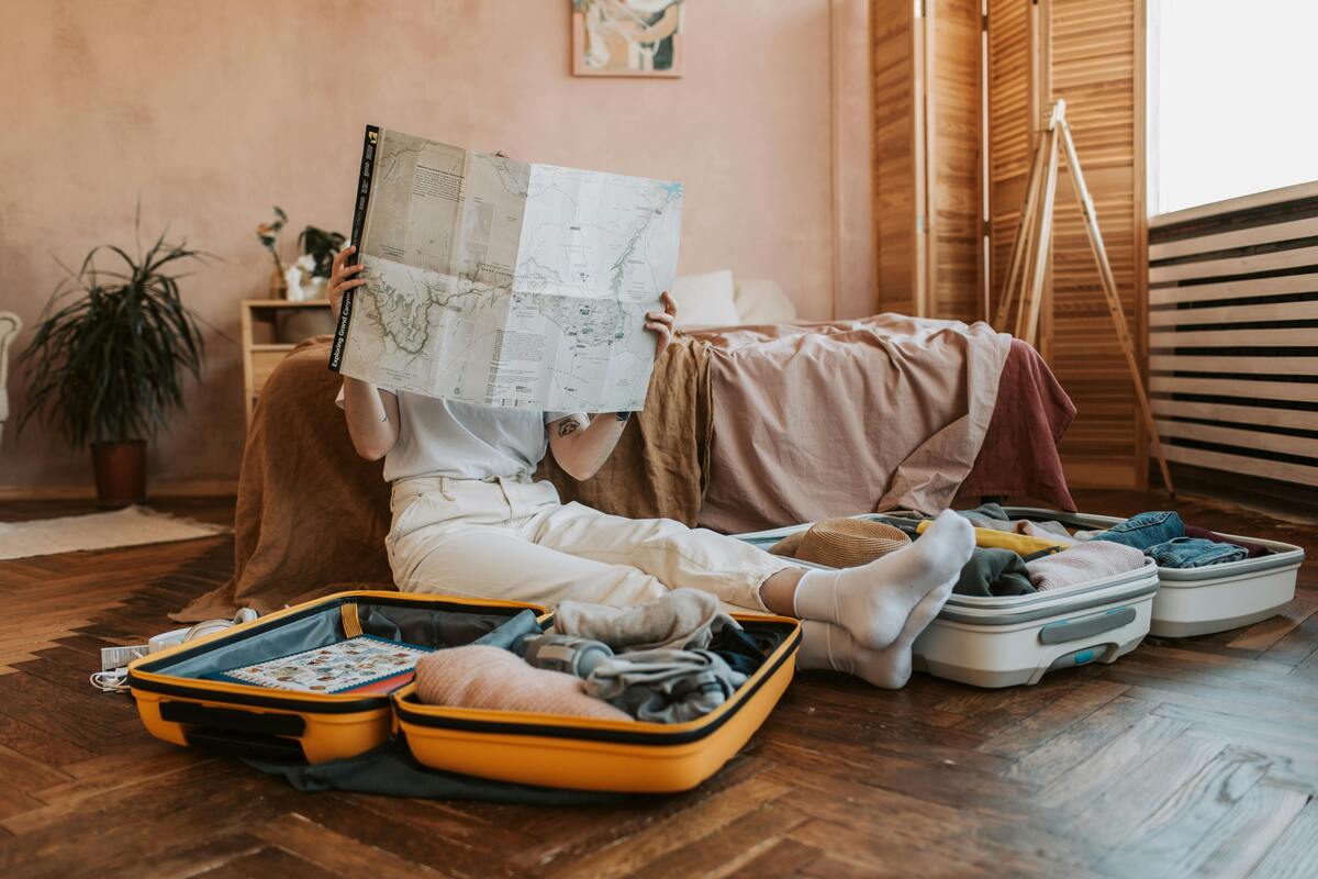 Person reading travel guide on floor surrounded by packed suitcases, curious about what to pack for Nashville trip