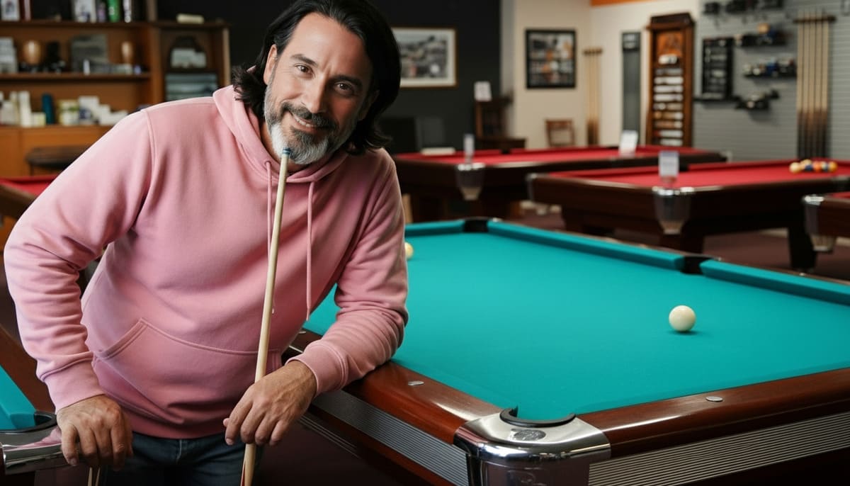 Man in pink hoodie smiling with pool cue at affordable pool halls in Nashville called Billiard Patio lounge