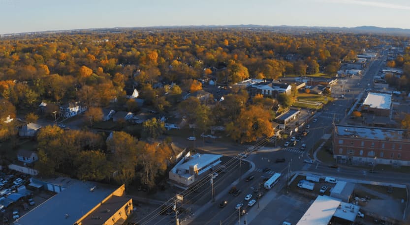 Golden hour drone shot of safest parts of East Nashville with autumn foliage, residential homes, and peaceful intersection