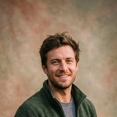 Avery Cole in green fleece jacket smiling outdoors against a warm earthy Tennessee background