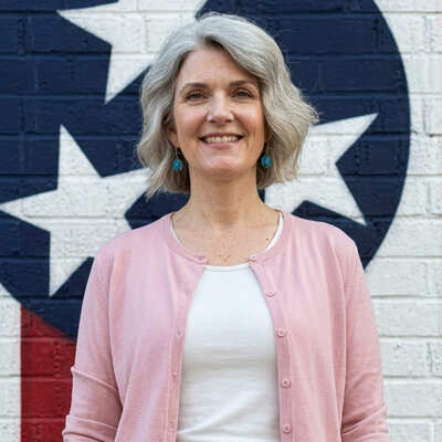 Clara Bennett in pink cardigan standing in front of Tennessee state flag mural in Nashville