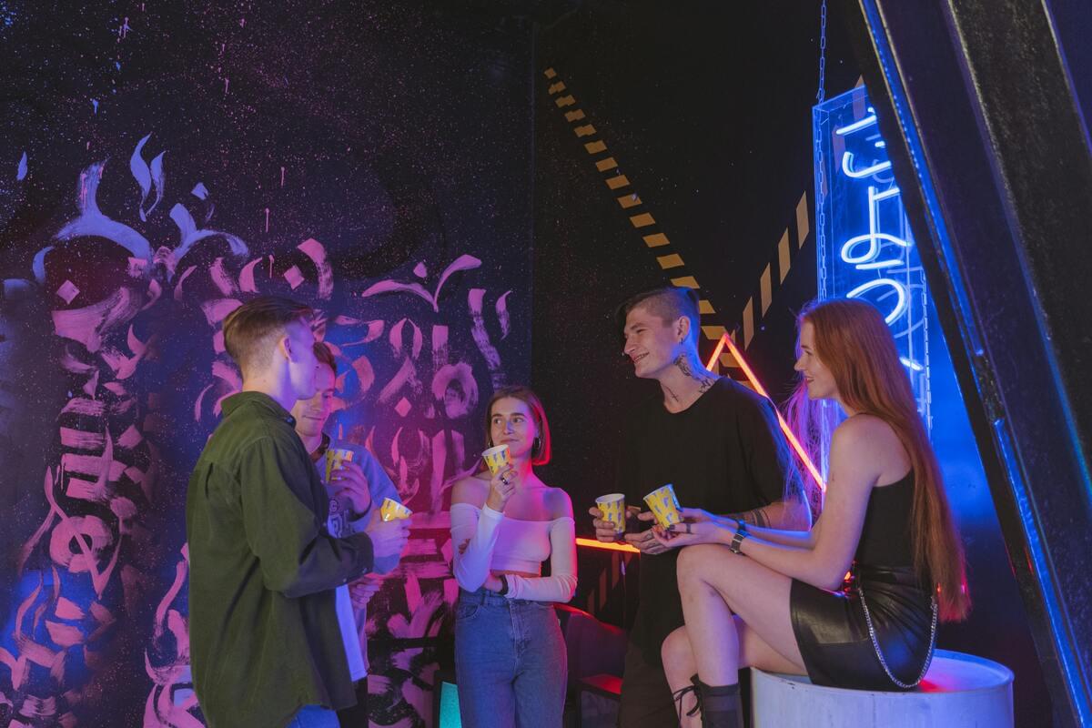 Young people cheerfully socializing at a vibrant Nashville nightlife venue with neon lights and artistic surroundings